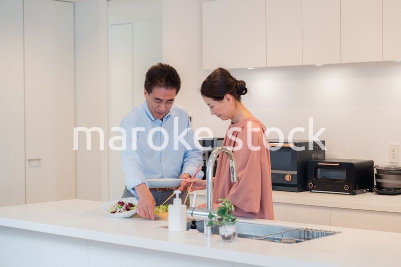 キッチンで一緒にクッキングを楽しむシニアの夫婦