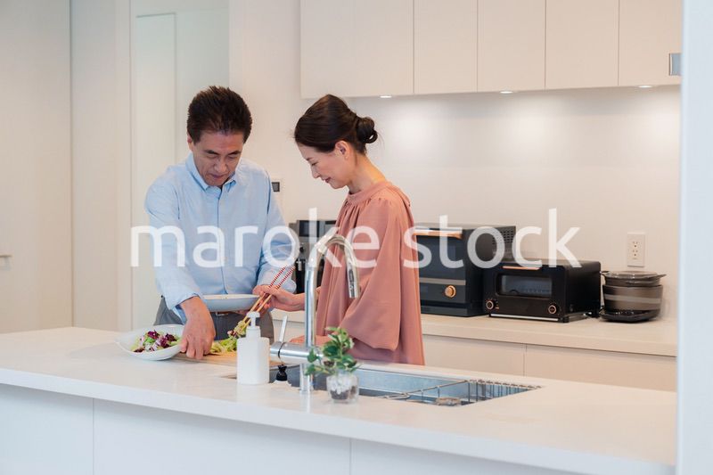 キッチンで一緒にクッキングを楽しむシニアの夫婦