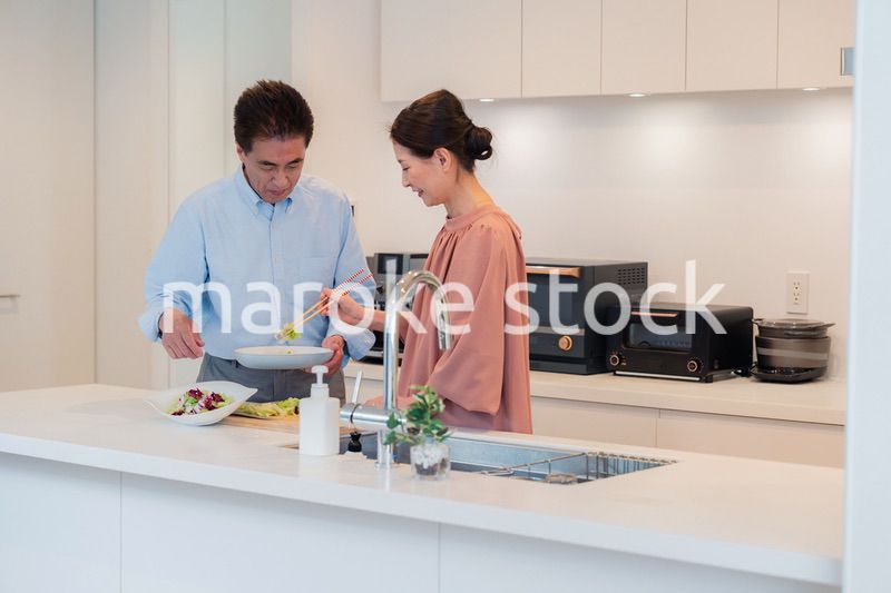 キッチンで一緒にクッキングを楽しむシニアの夫婦