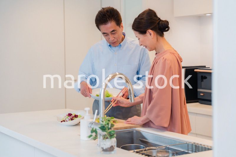 キッチンで一緒にクッキングを楽しむシニアの夫婦