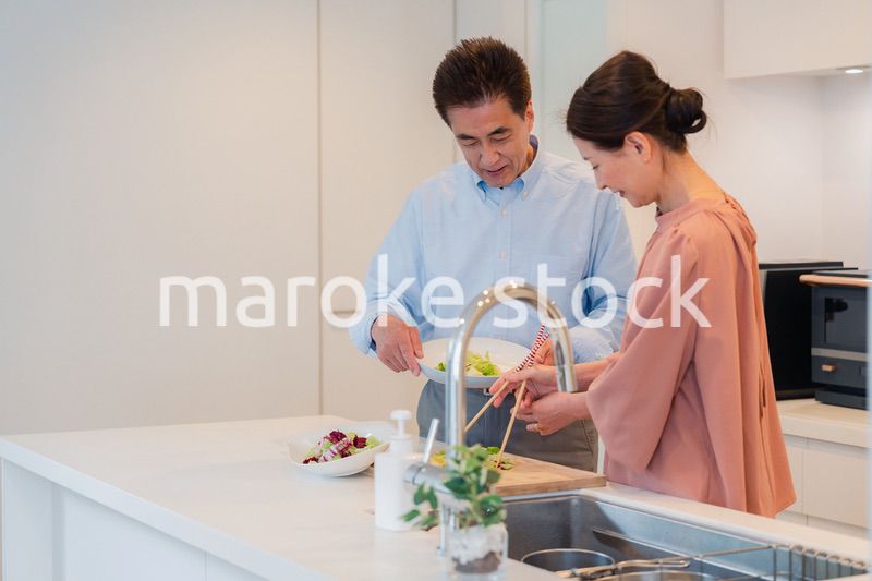 キッチンで一緒にクッキングを楽しむシニアの夫婦