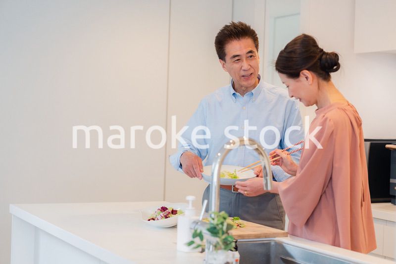 キッチンで一緒にクッキングを楽しむシニアの夫婦