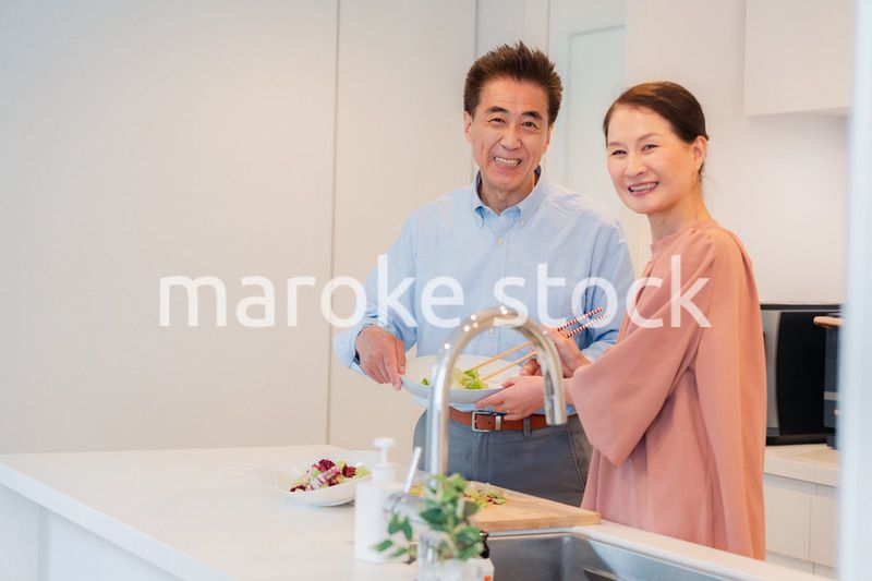 キッチンで一緒にクッキングを楽しむシニアの夫婦