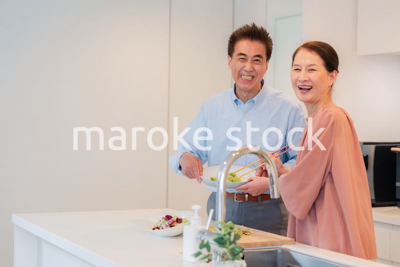 キッチンで一緒にクッキングを楽しむシニアの夫婦