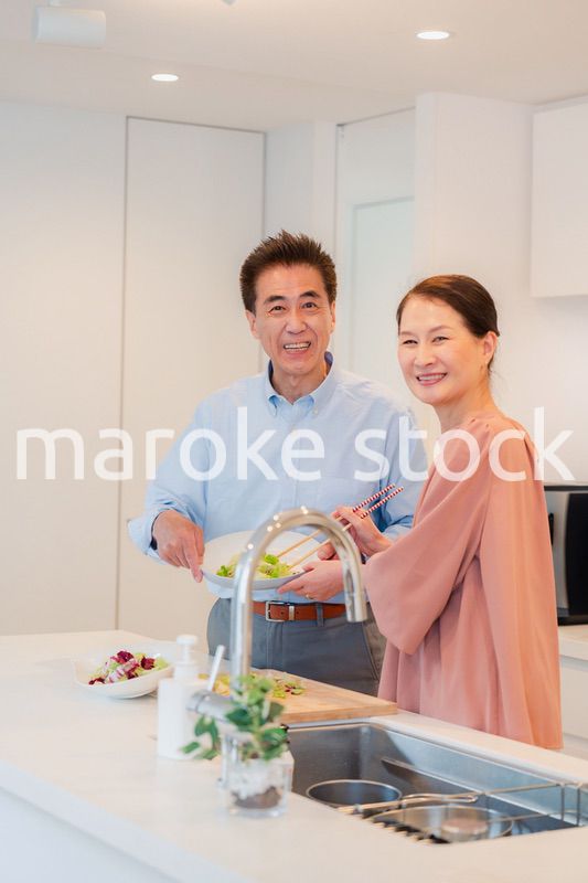 キッチンで一緒にクッキングを楽しむシニアの夫婦