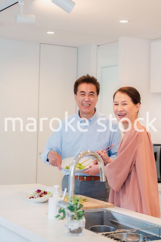 キッチンで一緒にクッキングを楽しむシニアの夫婦