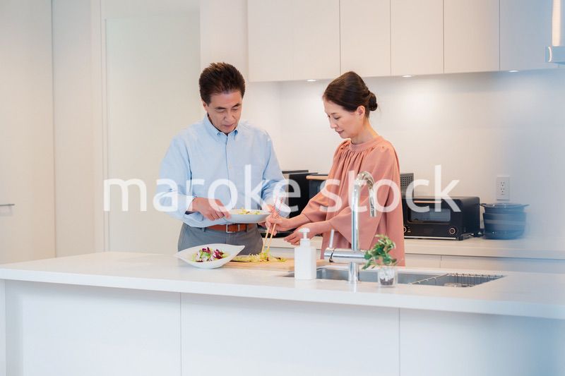 キッチンで一緒にクッキングを楽しむシニアの夫婦