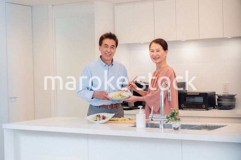 キッチンで一緒にクッキングを楽しむシニアの夫婦