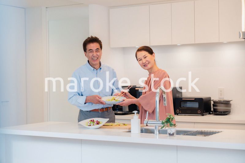 キッチンで一緒にクッキングを楽しむシニアの夫婦
