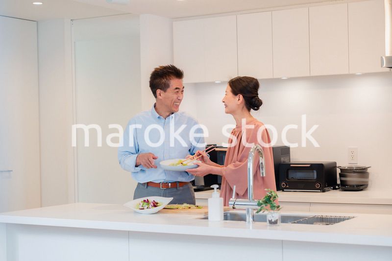 キッチンで一緒にクッキングを楽しむシニアの夫婦