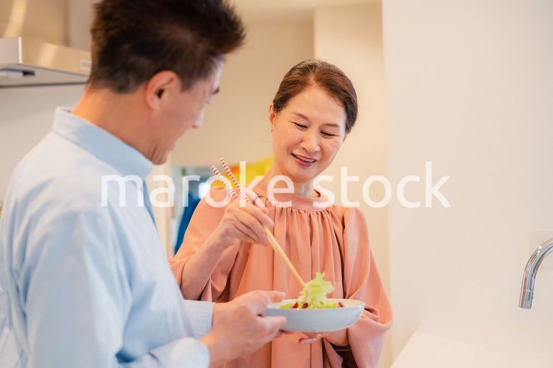 キッチンで一緒にクッキングを楽しむシニアの夫婦