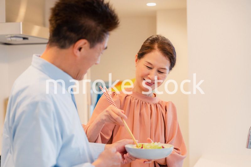キッチンで一緒にクッキングを楽しむシニアの夫婦