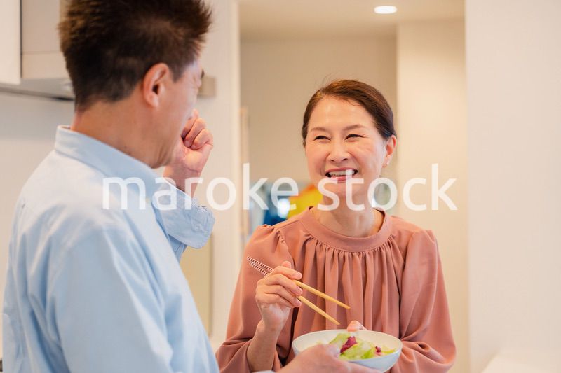 キッチンで一緒にクッキングを楽しむシニアの夫婦