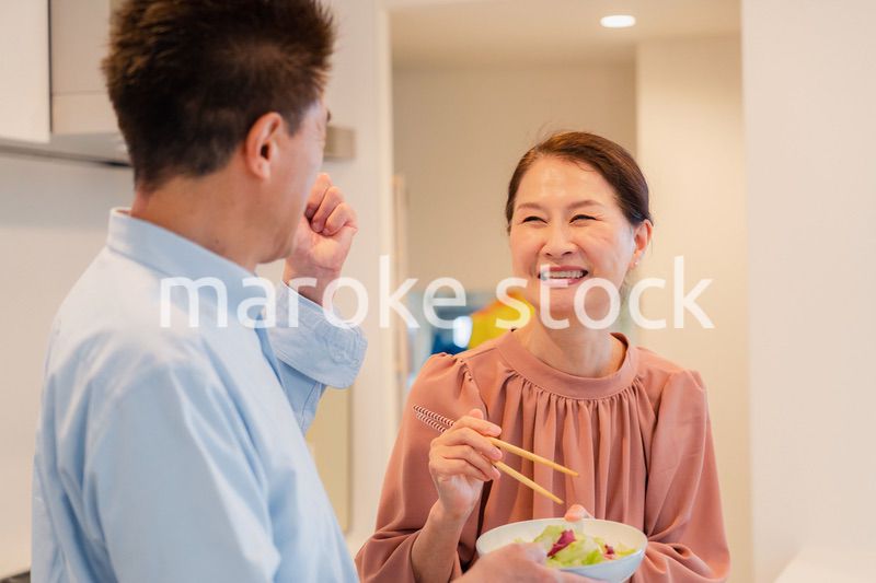 キッチンで一緒にクッキングを楽しむシニアの夫婦