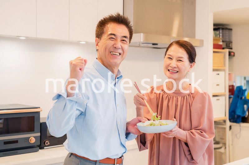 キッチンで一緒にクッキングを楽しむシニアの夫婦