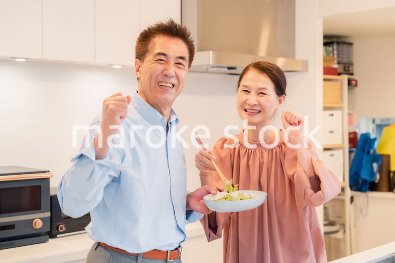 キッチンで一緒にクッキングを楽しむシニアの夫婦