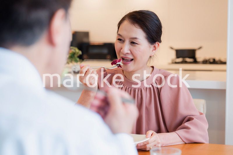 夫婦で楽しくご飯を食べる高齢女性