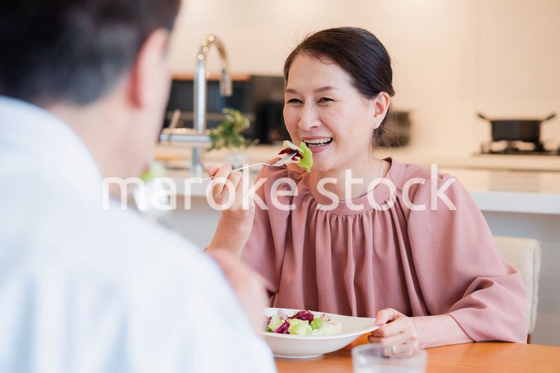 夫婦で楽しくご飯を食べる高齢女性