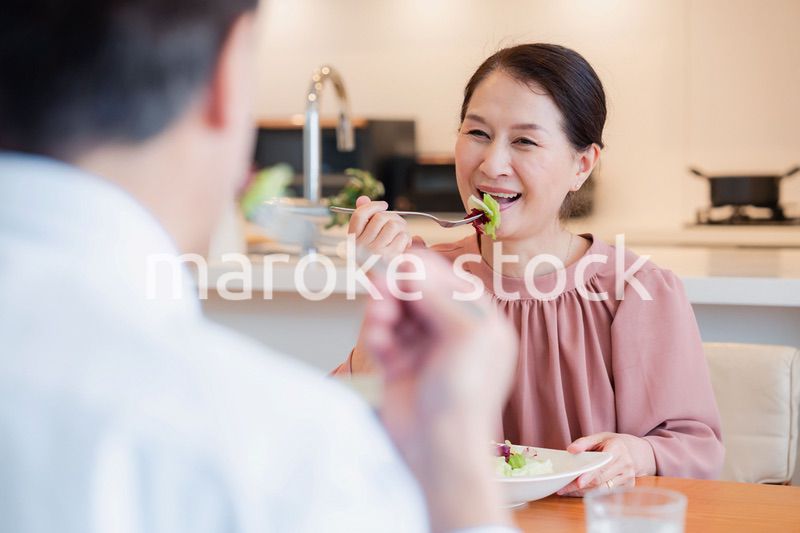 夫婦で楽しくご飯を食べる高齢女性