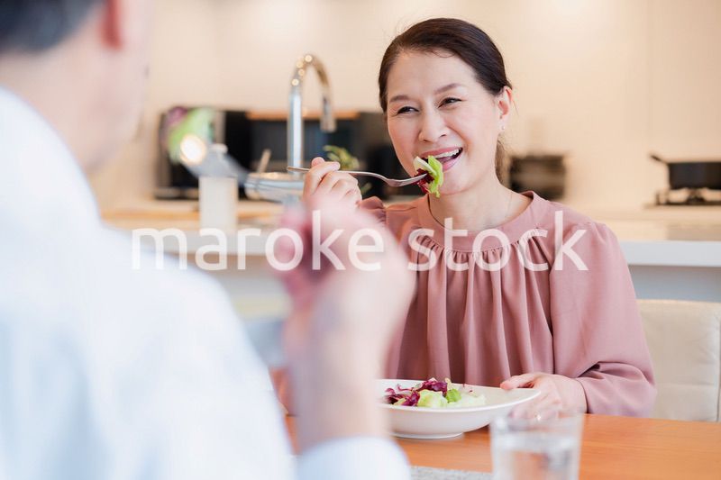 夫婦で楽しくご飯を食べる高齢女性