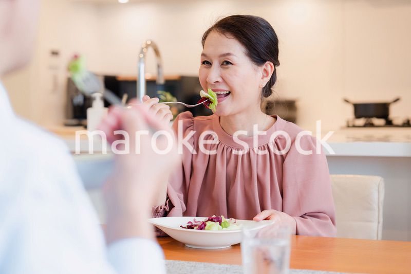 夫婦で楽しくご飯を食べる高齢女性