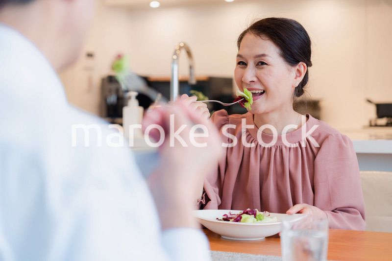夫婦で楽しくご飯を食べる高齢女性
