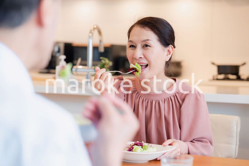 夫婦で楽しくご飯を食べる高齢女性