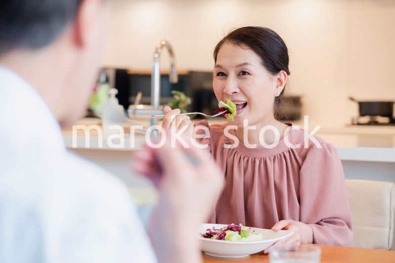 夫婦で楽しくご飯を食べる高齢女性