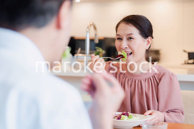 夫婦で楽しくご飯を食べる高齢女性