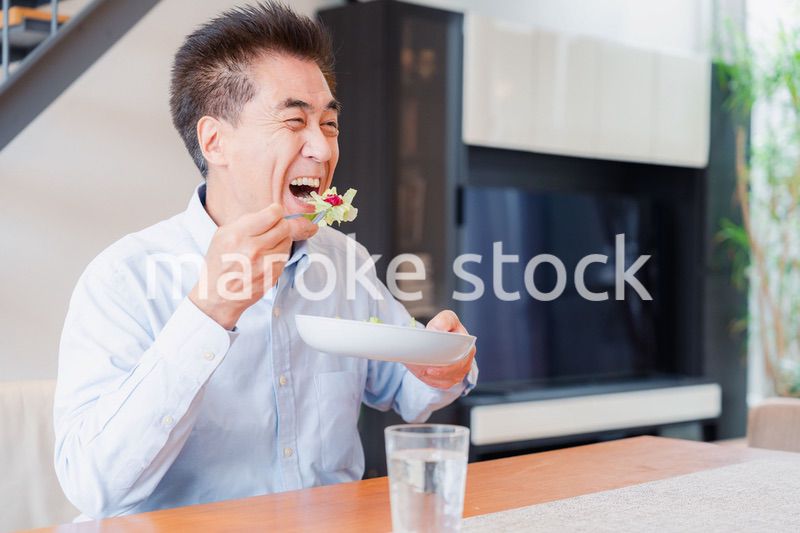 サラダをおいしく食べる高齢の男性