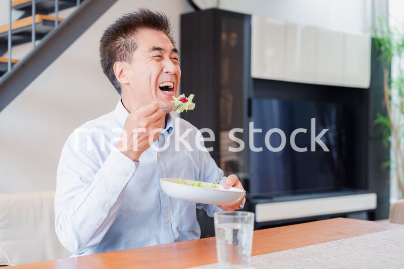 サラダをおいしく食べる高齢の男性