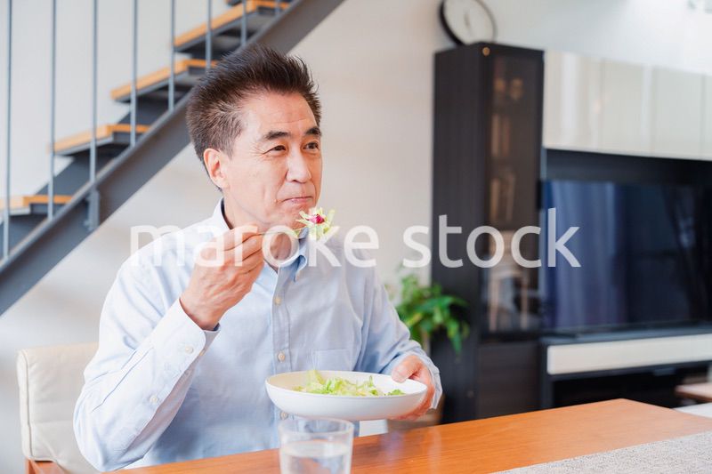 サラダをおいしく食べる高齢の男性