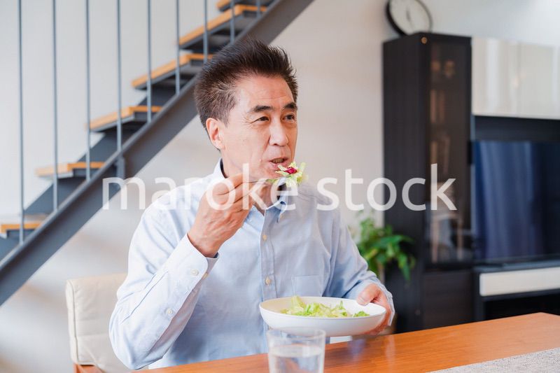 サラダをおいしく食べる高齢の男性