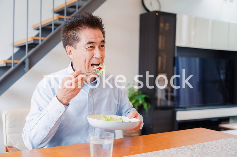 サラダをおいしく食べる高齢の男性