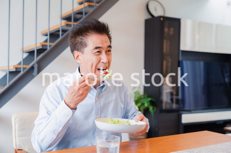 サラダをおいしく食べる高齢の男性