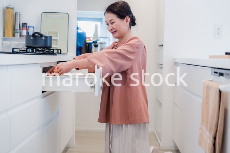 キッチンの収納を工夫するシニアの女性