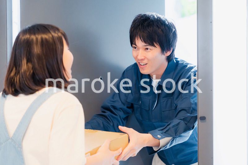 笑顔で宅配便の配達をする若い男性