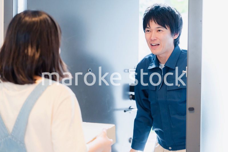 笑顔で宅配便の配達をする若い男性