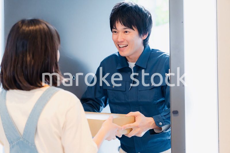 笑顔で宅配便の配達をする若い男性
