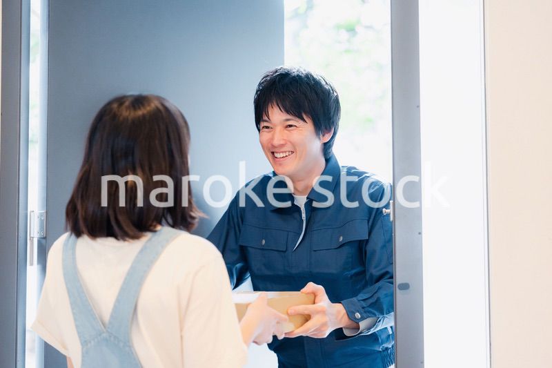 笑顔で宅配便の配達をする若い男性