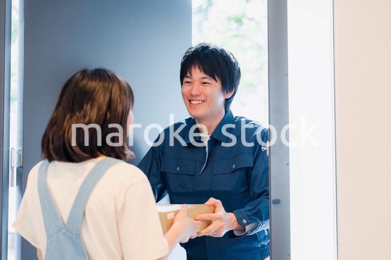 笑顔で宅配便の配達をする若い男性