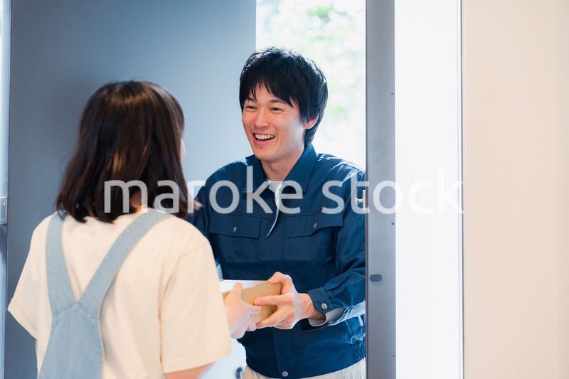 笑顔で宅配便の配達をする若い男性