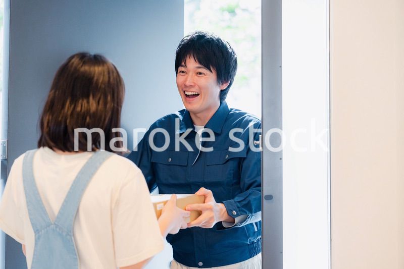 笑顔で宅配便の配達をする若い男性