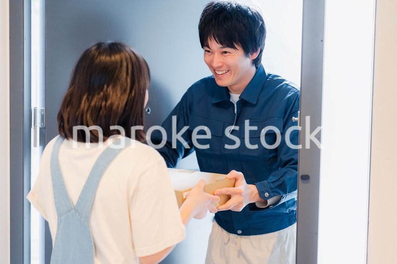 笑顔で宅配便の配達をする若い男性