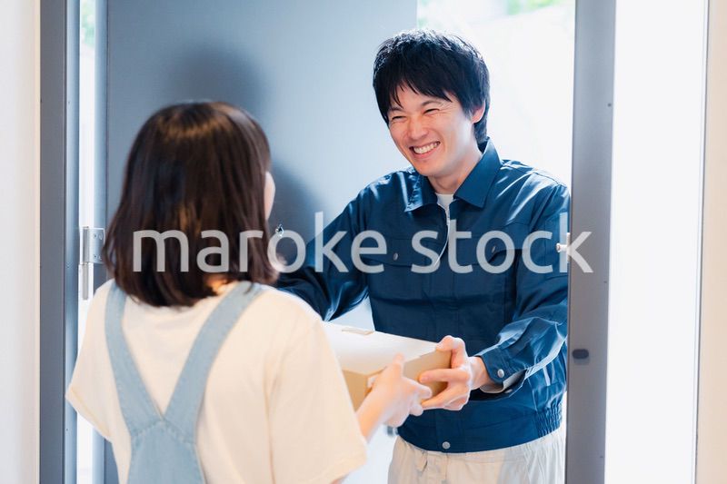 笑顔で宅配便の配達をする若い男性
