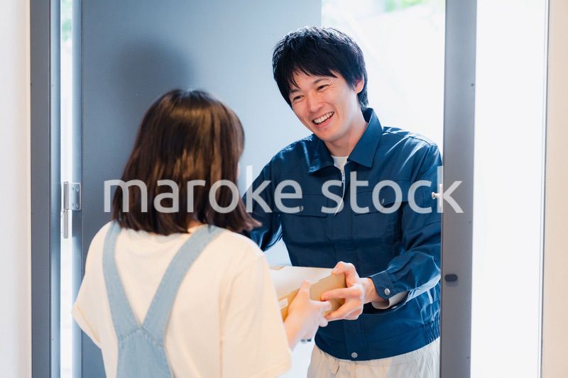 笑顔で宅配便の配達をする若い男性