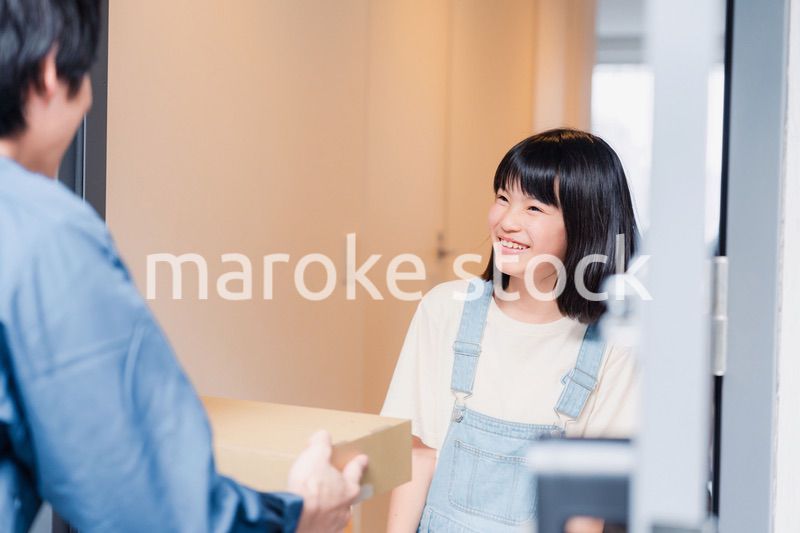 家で宅配便を受け取る小学生の女の子