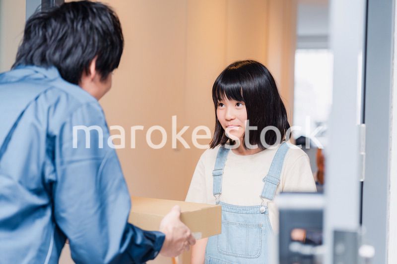 家で宅配便を受け取る小学生の女の子