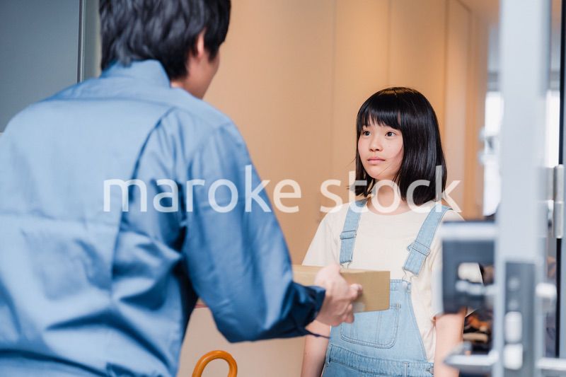 家で宅配便を受け取る小学生の女の子