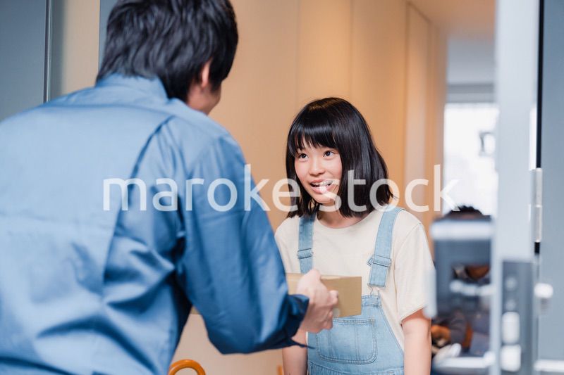 家で宅配便を受け取る小学生の女の子